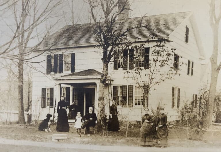 Reynolds Farm and family sitting outside of their house, black and white photo, wide shot.