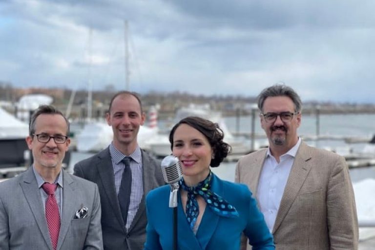 Margi and the Dapper Dots standing on a dock at Prime; dressed very formally.
