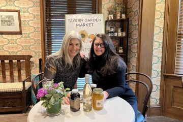 Dianne Niklaus & Meredith Geller pictured in the Cafe in front of Tavern Garden Market sign; displaying garden market goods jams and wine.